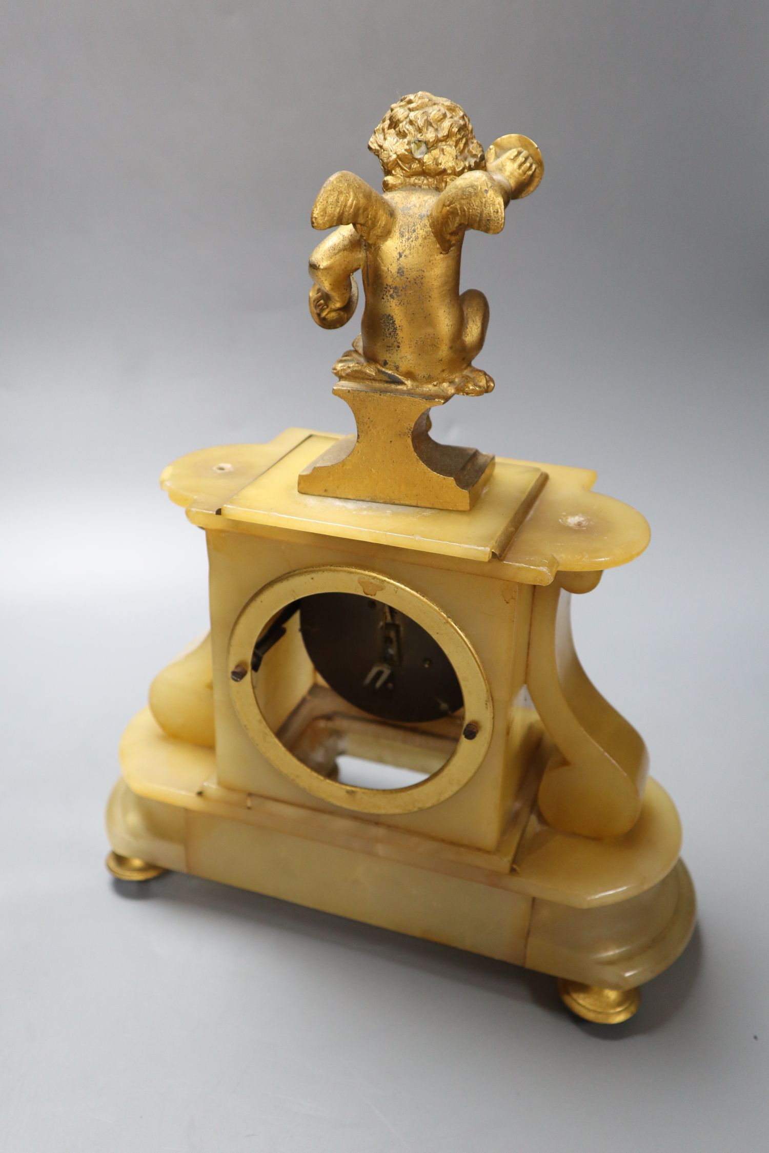 A late 19th century alabaster mantel clock, with gilt metal cherub surmount, French timepiece movement, 32cm